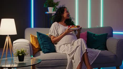 pregnant woman enjoying dessert on the sofa at night