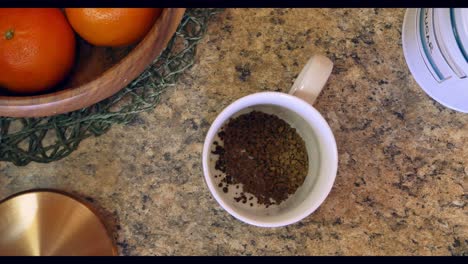 topshot of hand making instant coffee in mug with milk on kitchen counter top