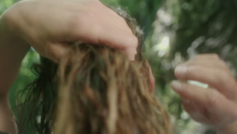 female running hands through dark wet hair in forest shot in slowmotion