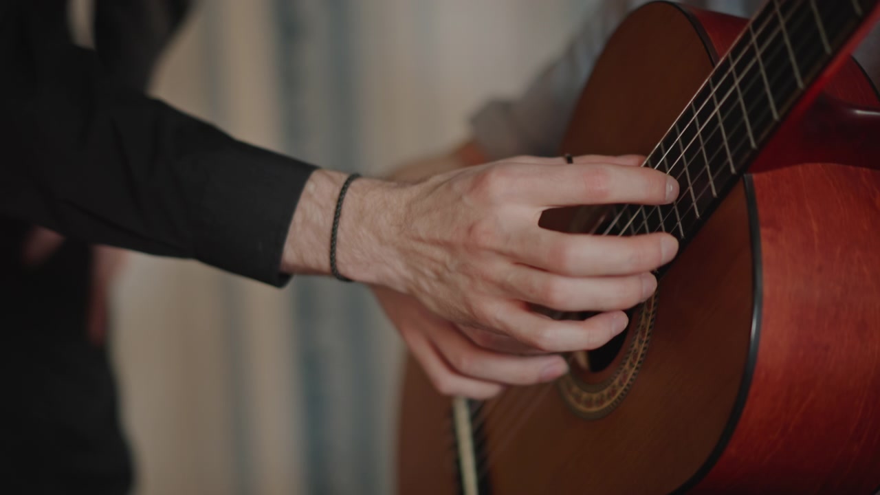 Closeup of hand executing detailed guitar fingerpicking skills during session. Educational demonstration focusing on accurate guitar fingerstyle technique with warm lighting ambiance