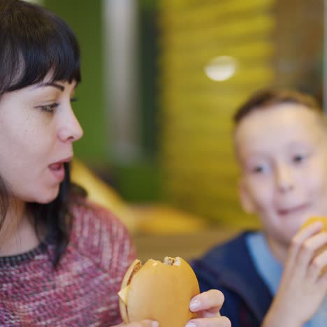 woman with child eats burgers in fast food restaurant. family in a fast food restaurant