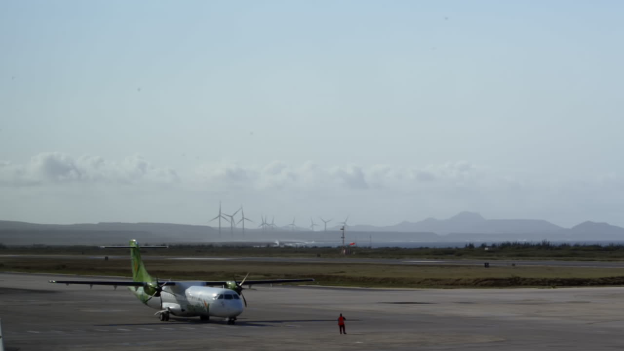 Airplane on Airport Runway with Wind Turbines and Ocean View