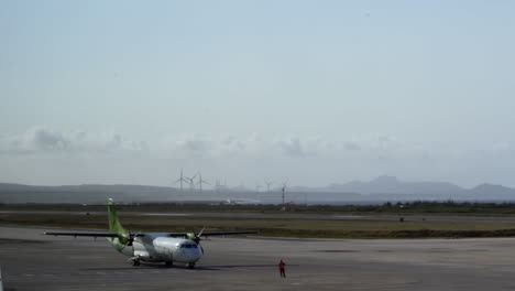 airplane on airport runway with wind turbines and ocean view