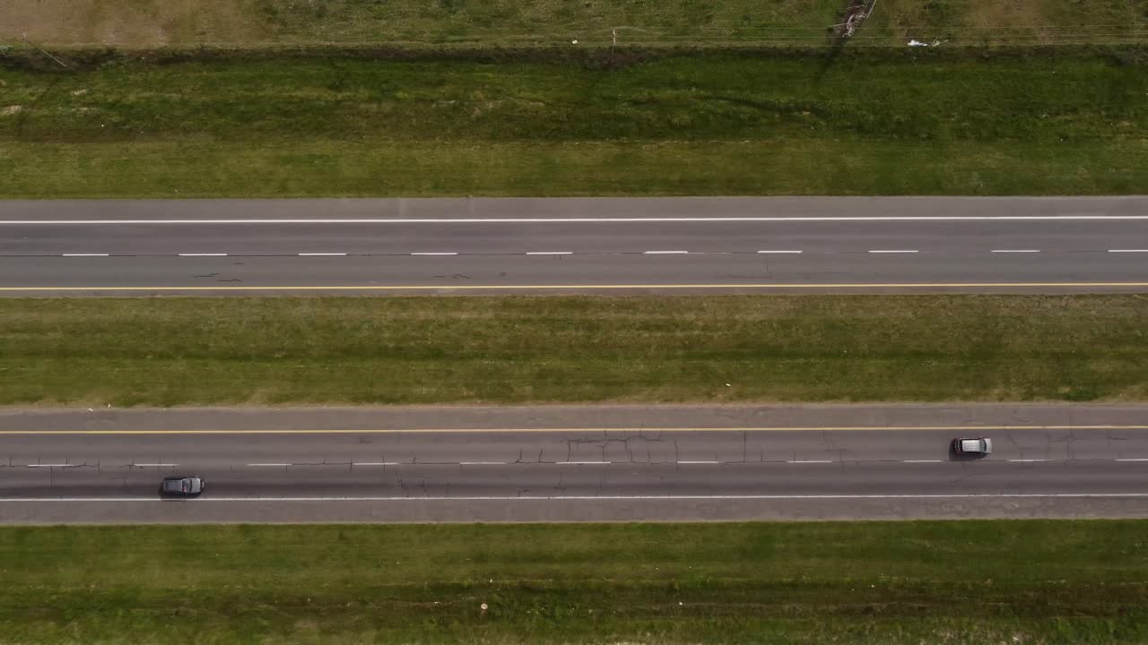 화창한 날 교통량이 많은 시골 도로의 공중 하향식 - 고속도로 옆의 푸른 잔디밭 - 4k 비행
