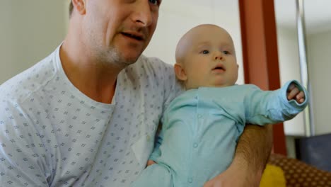 father and baby boy watching television in living room 4k