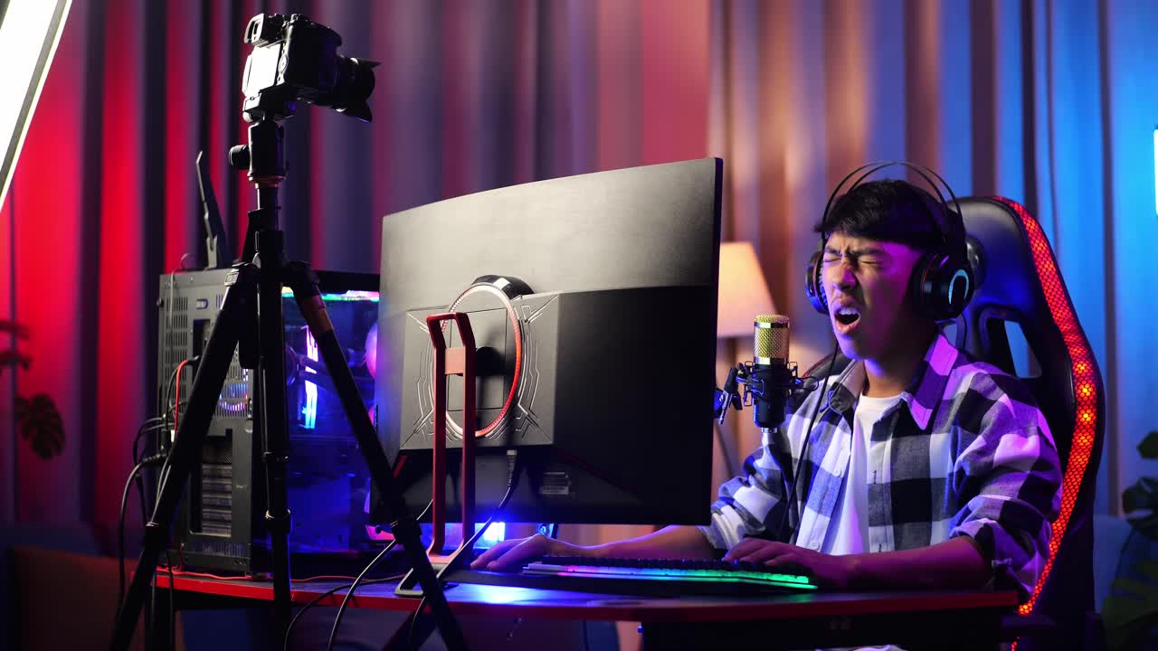 Asian Boy Streamer Playing Game Over Network On Personal Computer. Yawning And Sleeping, Live Stream Video Game, Desk Illuminated By Rgb Led Strip Light