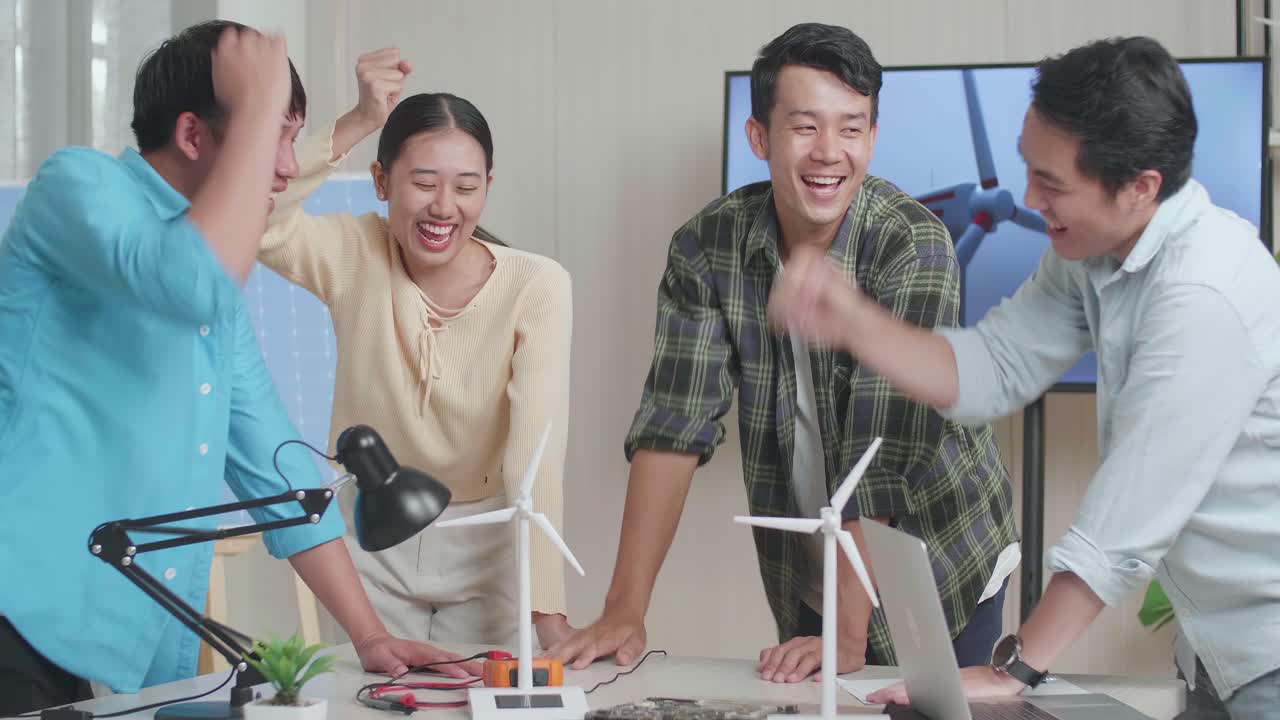 아시아 엔지니어 그룹이 사무실에서 풍력 터빈에 대해 작업하는 동안 함께 손을 고 있습니다.