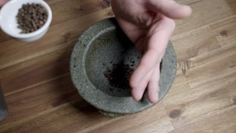 A-chef-puts-black-pepper-in-a-mortar-and-starts-to-crush-it