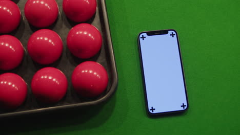 snooker balls and phone on a green table
