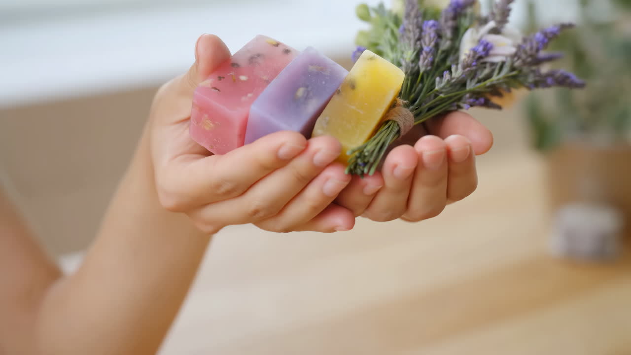 Mani che tengono saponette artigianali colorate e un bouquet di lavanda