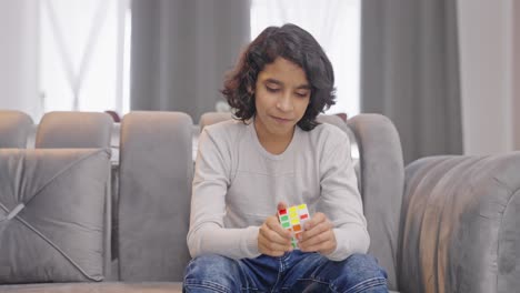 happy indian kid teenager boy trying to solve rubik's cube