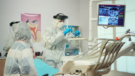 dentist in ppe suit standing near girl patient talking with mother