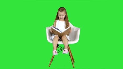 niña estudiante sentada y leyendo un libro en una pantalla verde, clave de croma