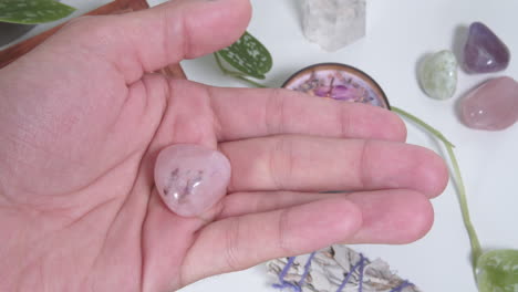pink petalite tumbled stone in the palm of a hand