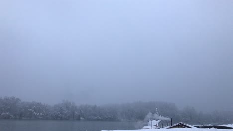 Old small river winter cottage with chimney smoke and Danube river background