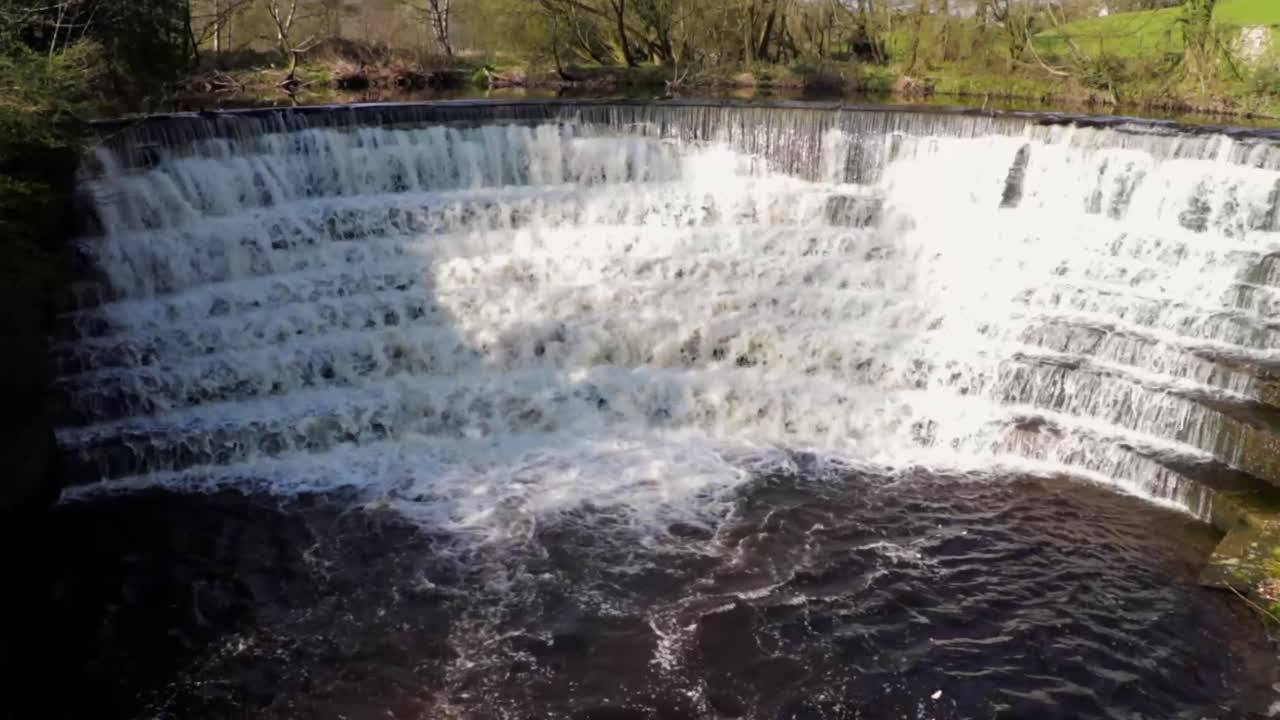 나무와 녹지로 둘러싸인 돌계단 폭포를 흐르는 물