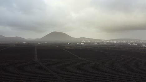 aerial landscape of black soil and ash on the ground near a volcano