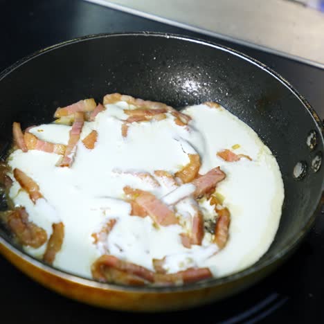 frying bacon pieces in a pan. crispy pieces of delicious bacon are fried in a hot skillet. unhealthy food