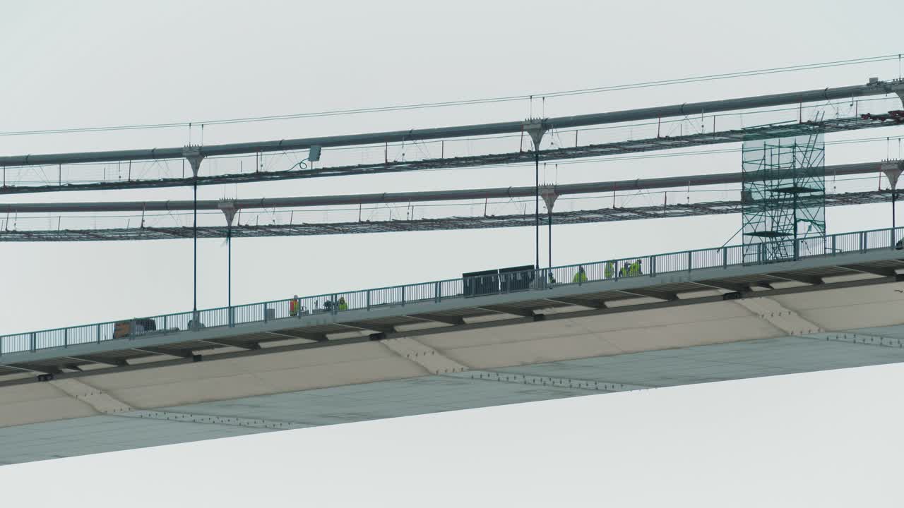 건설 중인 큰 현수교에 있는 작업자들의 정적인 클로즈업 샷, 중간 부분