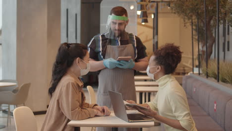 man serving table with two women