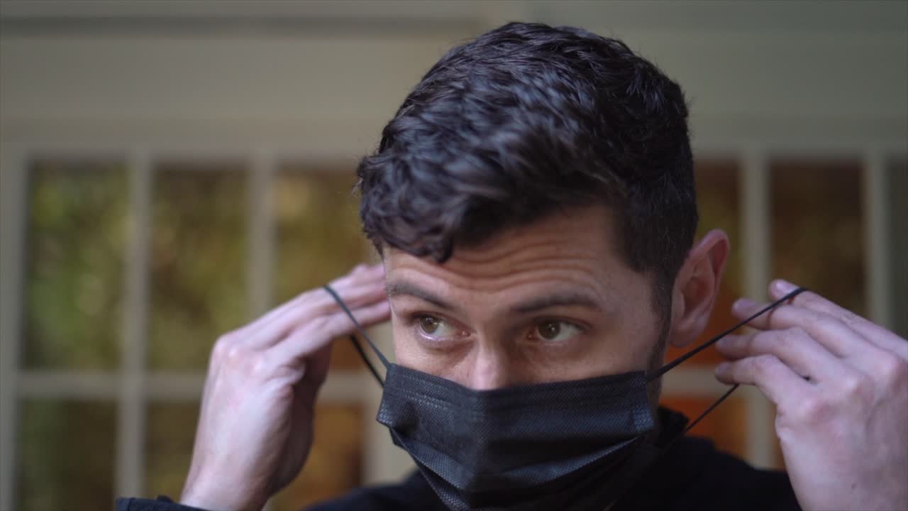 매력적인 젊은 성인 남성은 바이러스로부터 보호하기 위해 검은 얼굴 마스크를 착용합니다 - 느린 동작 - 2020년 세계적 유행병