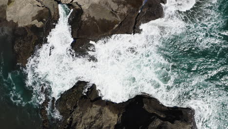 descending on small inlet as powerful waves crashing on the rocks