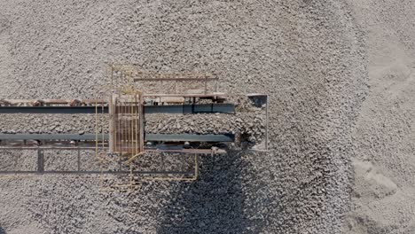 top down aerial static footage of rocks falling off a conveyor belt in a quarry.