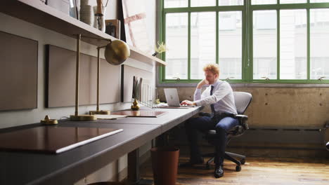 young businessman using laptop alone in a small office