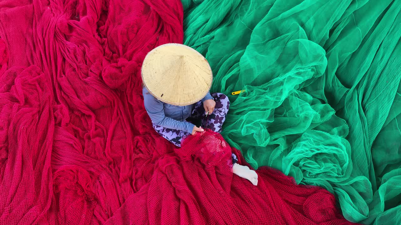 una mujer está tejiendo una red en una gran y hermosa red de pesca turquesa en el muelle de hon ro, ciudad de nha trang, provincia de khanh hoa, vietnam central