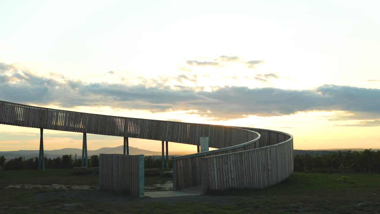 Lookout point wooden building entrance to wooden construction Kobyli Vrch in the background moving clouds and setting sun during autumn evening area of South Moravia