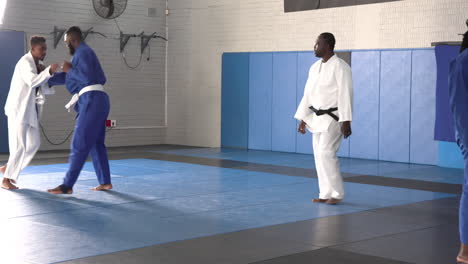 practicing judo, two men sparring while instructor observes in dojo
