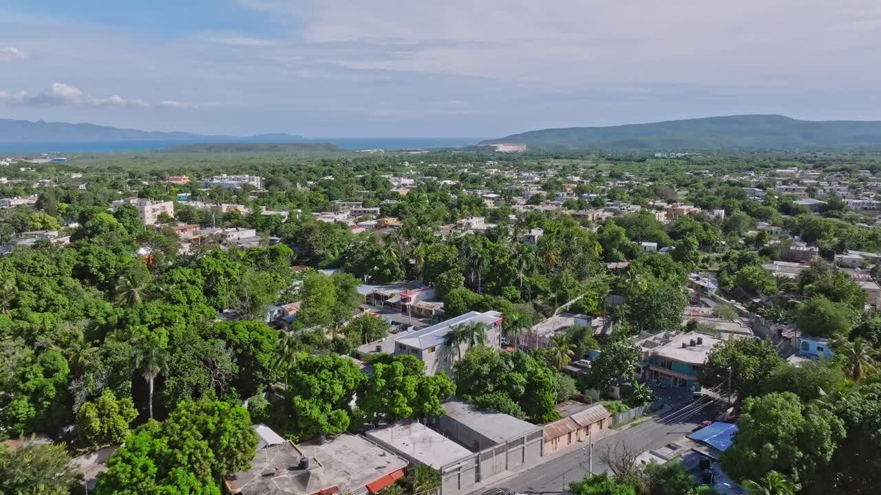 sobrevuelo aéreo al pueblo de azua con árboles verdes y edificios antiguos en la república dominicana en un día soleado