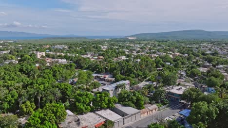 aerial flyover azua village with green trees and old buildings on dominican republic at sunny day