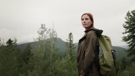 A-beautiful-female-girl-hiker-with-a-backpack-in-the-mountains-looks-over-her-shoulder