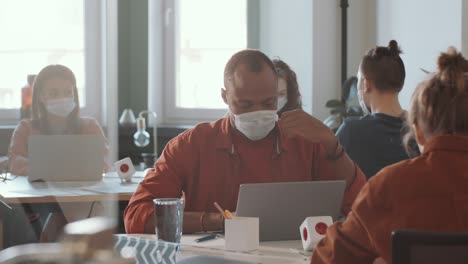 african american man in face mask working in open space office