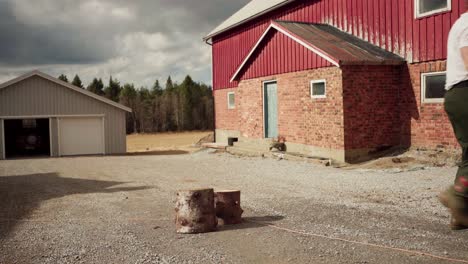 man holding and carrying firewood logs - wide shot
