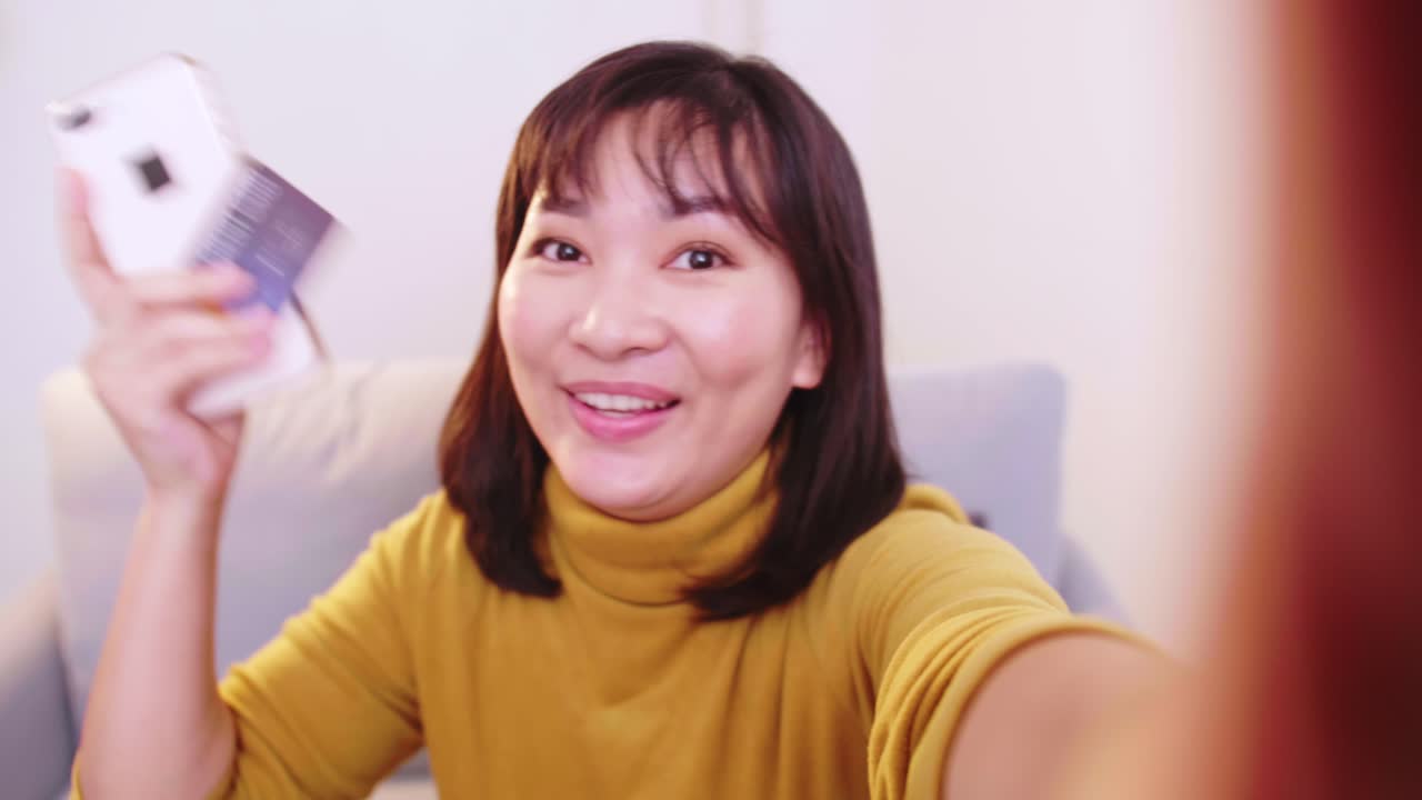 신용 카드와 휴대폰을 보여주는 친구들과 화상 통화를 하는 아시아 여성