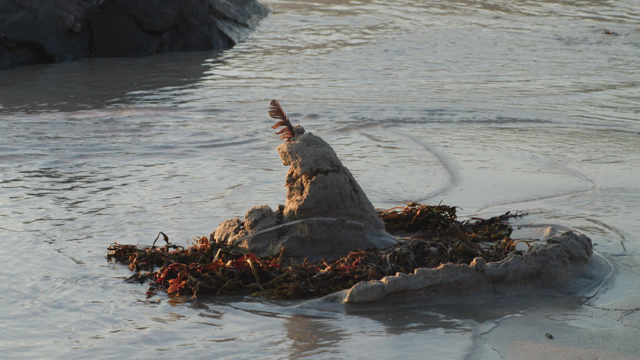 маленький песчаный замок на пляже при закате