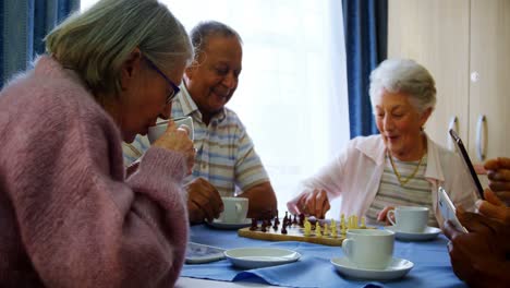 senior citizens using mobile phone and digital tablet while playing chess 4k
