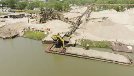 loading dry bulk cargo barge with sand and gravel in arkansas river