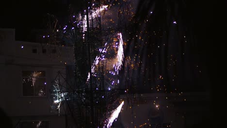 low angle shot of celebrations underway in a distance of burning effigy with crackers at night time