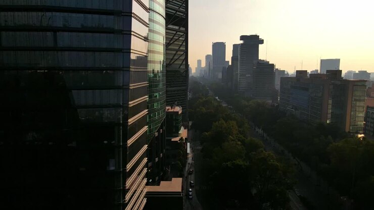 Tomada de drone com travelling para a direita de um edifício de vidro vanguardista e da Avenida Paseo de la Reforma, Cidade do México