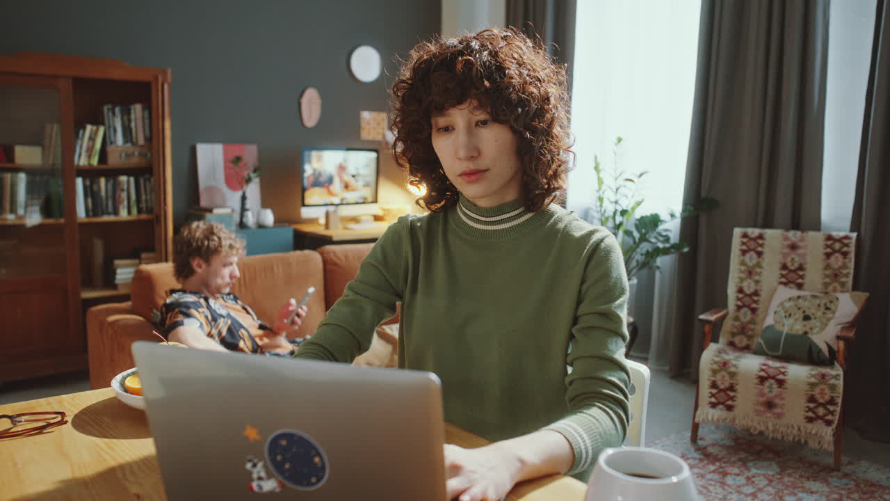 Young Asian Female Freelancer Working Remotely on Laptop at Home