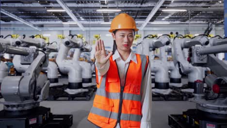 mujer ingeniera en una fábrica, deteniendo a los robots