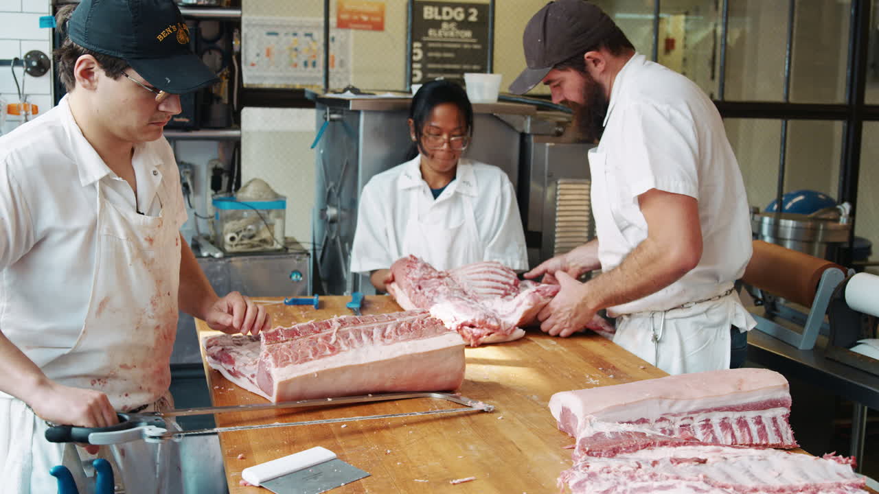 Three butchers preparing meat at a butcher's shop