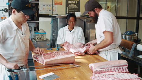 tres carniceros preparando carne en una carnicería