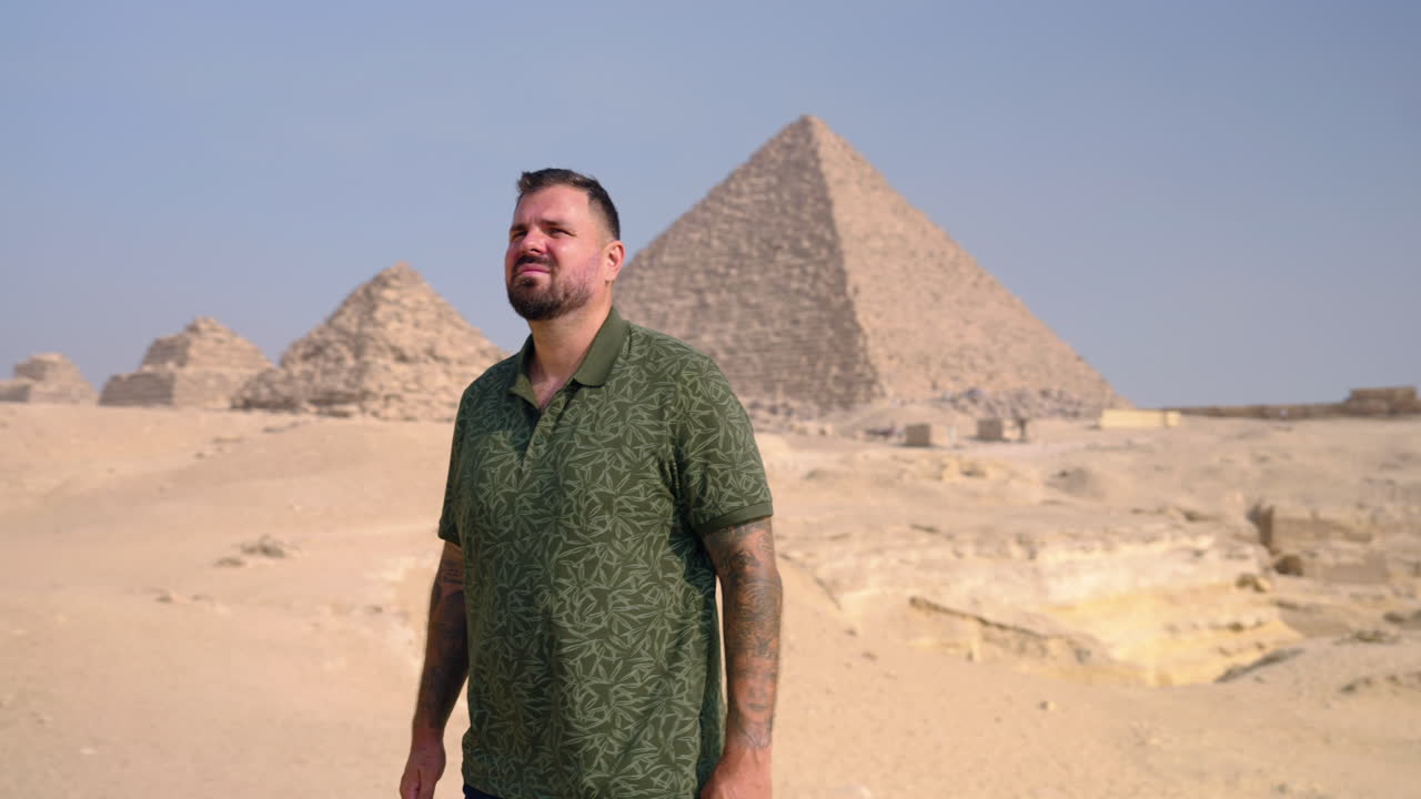Tourist On A Windy Desert Of Giza Plateau With Pyramid Complex In Egypt. Orbiting Shot