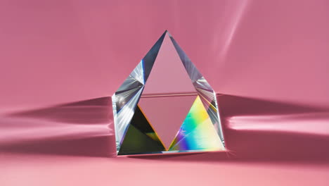 glass prism with rainbow spectrum on pink background
