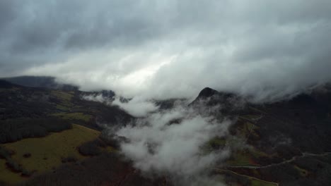 nuvole che coprono la valle alpina in una giornata di pioggia autunnale, prati di erba secca e alberi spogli