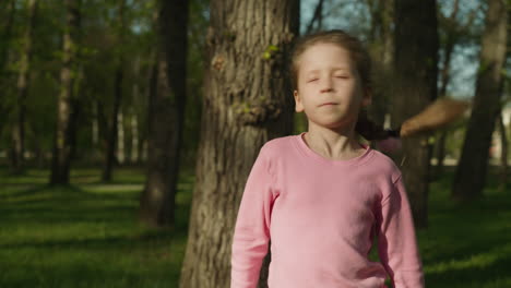 funny little girl shakes head and waves stick in spring park